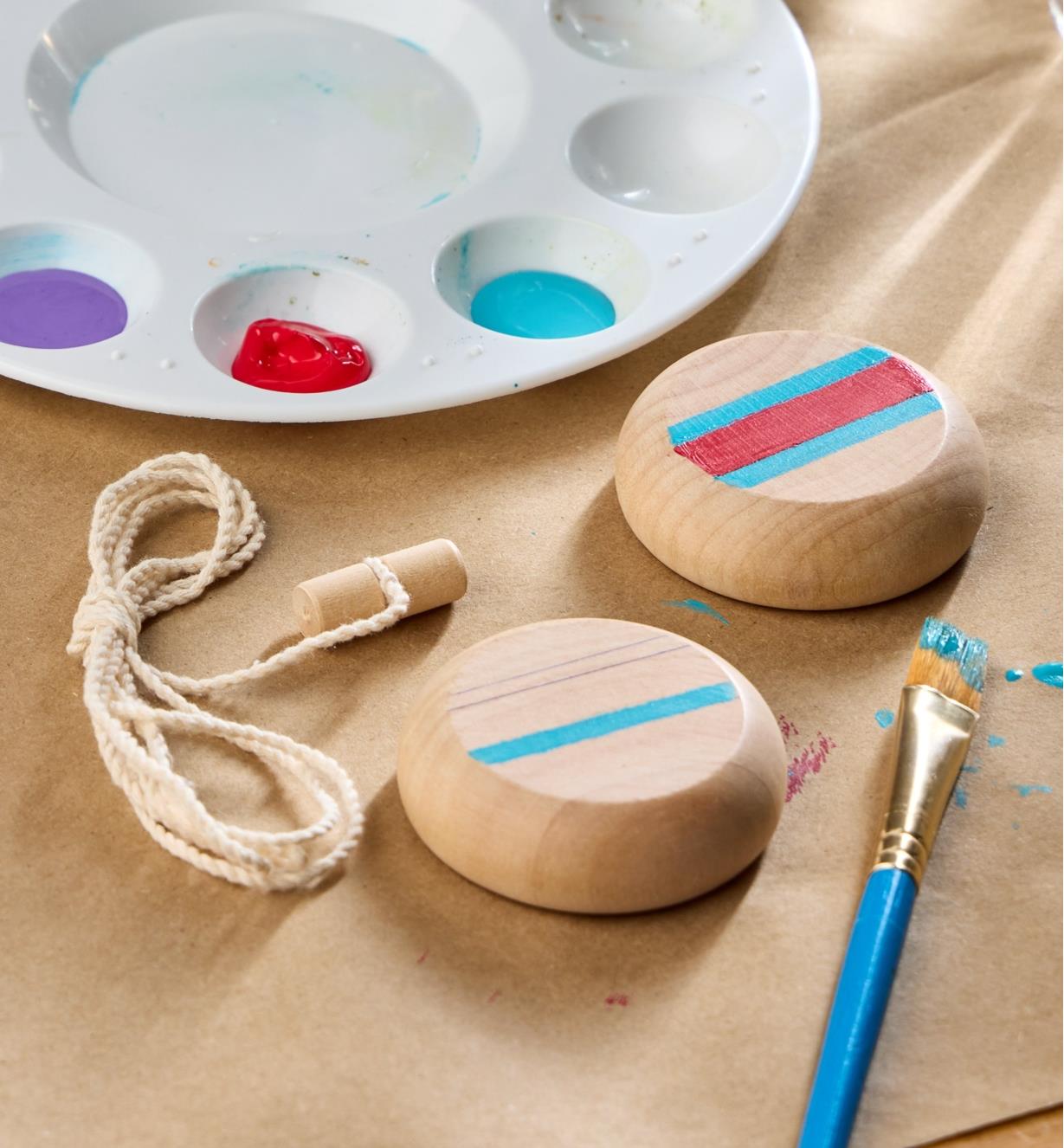 Painted yo-yo kit components next to a paint brush and paint palette