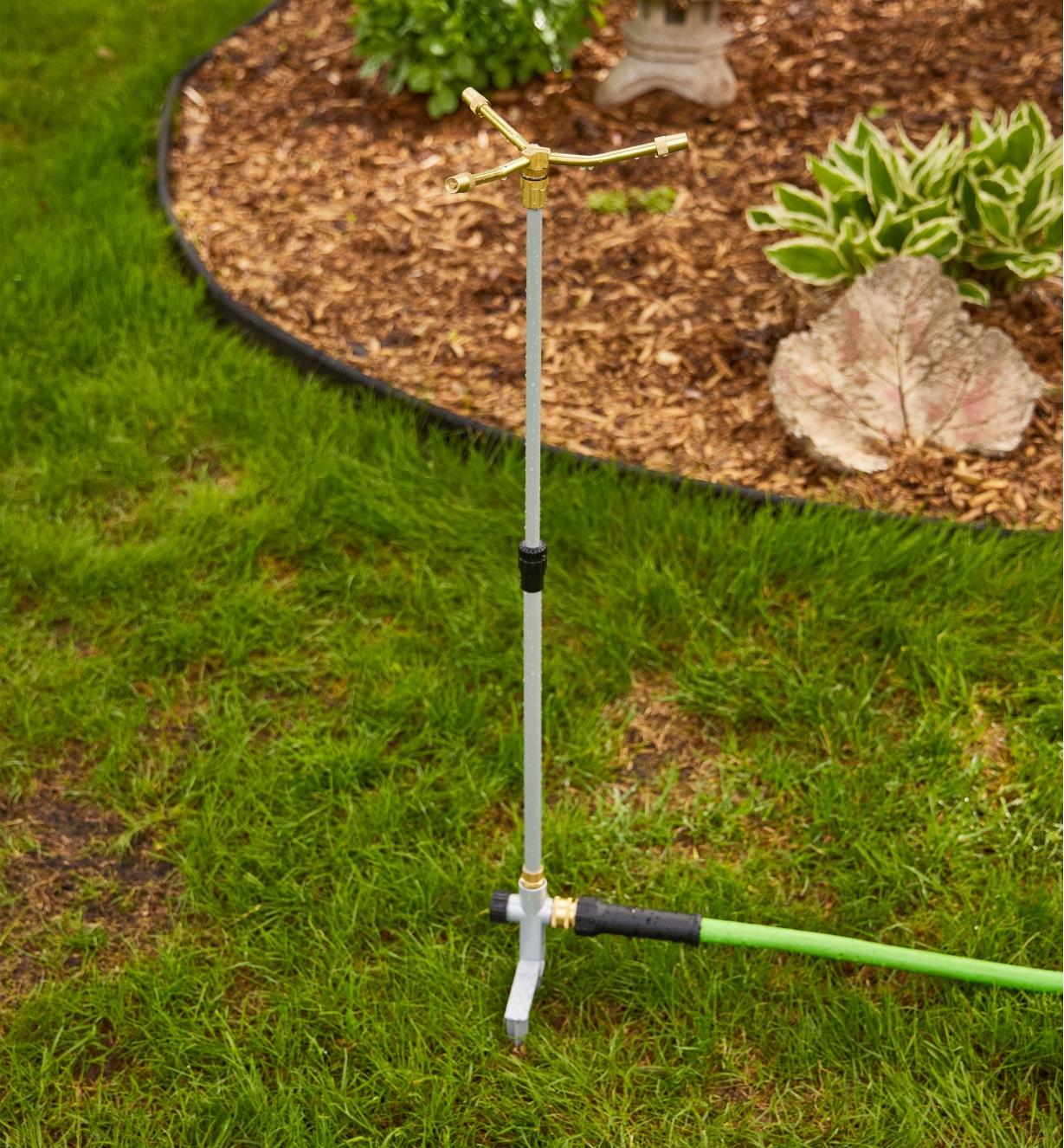 A telescoping sprinkler positioned in grass