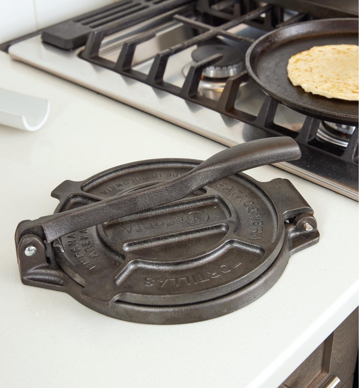 The tortilla press sits on a countertop next to a stove