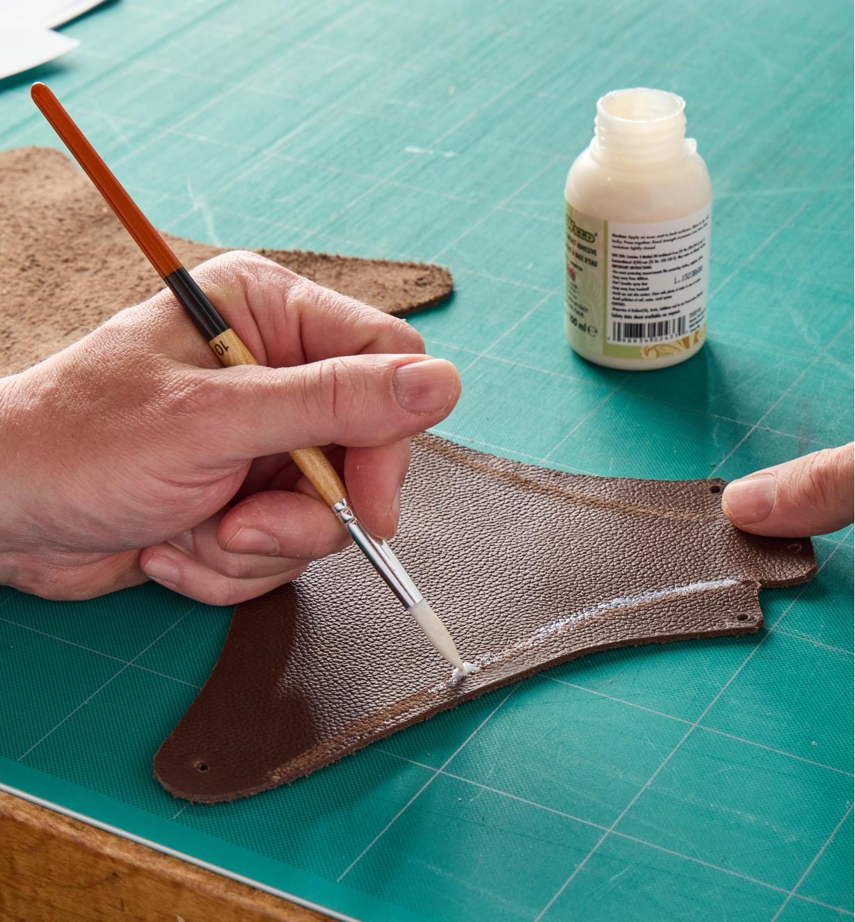 Applying glue to a piece of leather using a small paintbrush