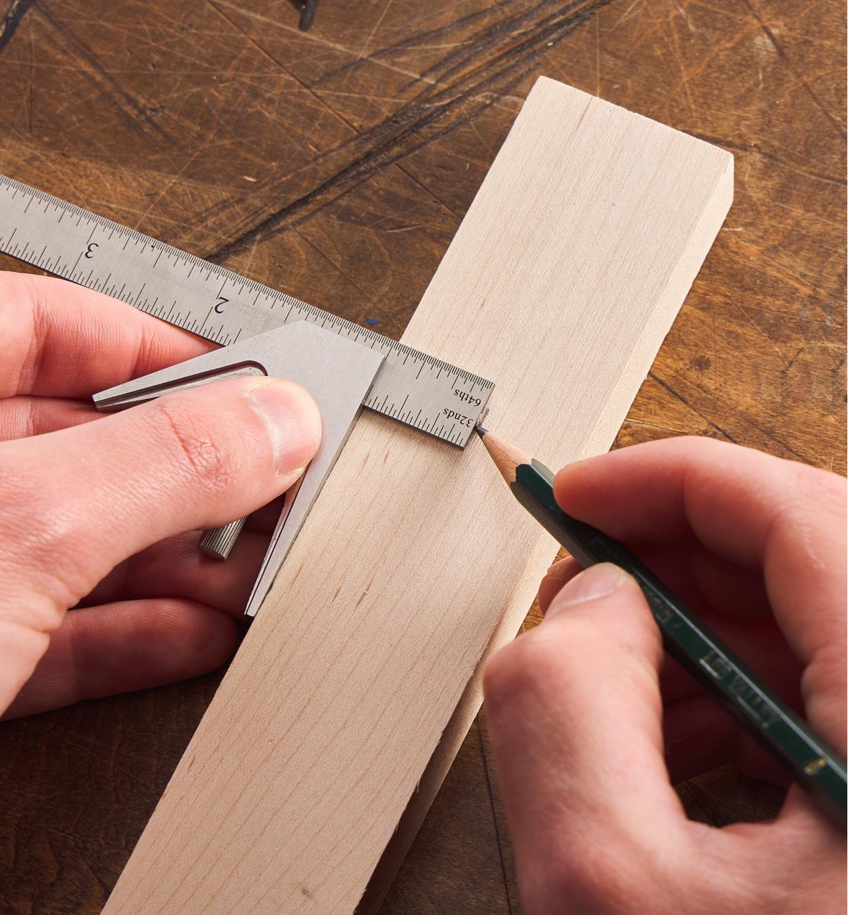 Personne utilisant une équerre combinée de 4 po Lee Valley pour faire une marque de crayon à une distance précise du bord d'une pièce de bois