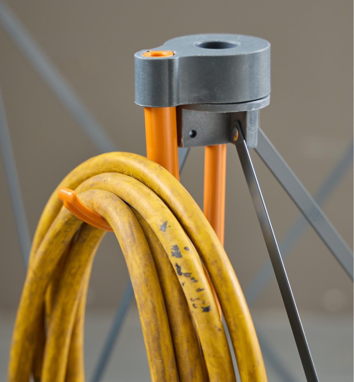 A close-up view of an extension cord hung on a hook mounted on the leg cap of a Bora Centipede table