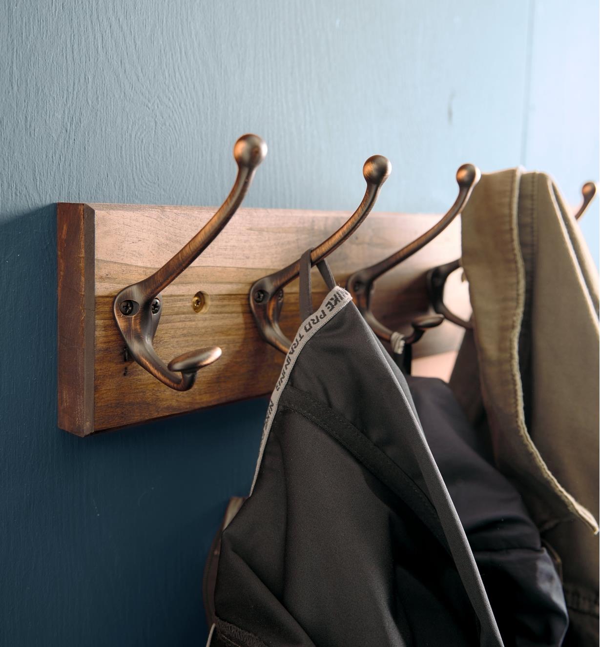 Double hooks on a board attached to a wall, with jackets hanging from them