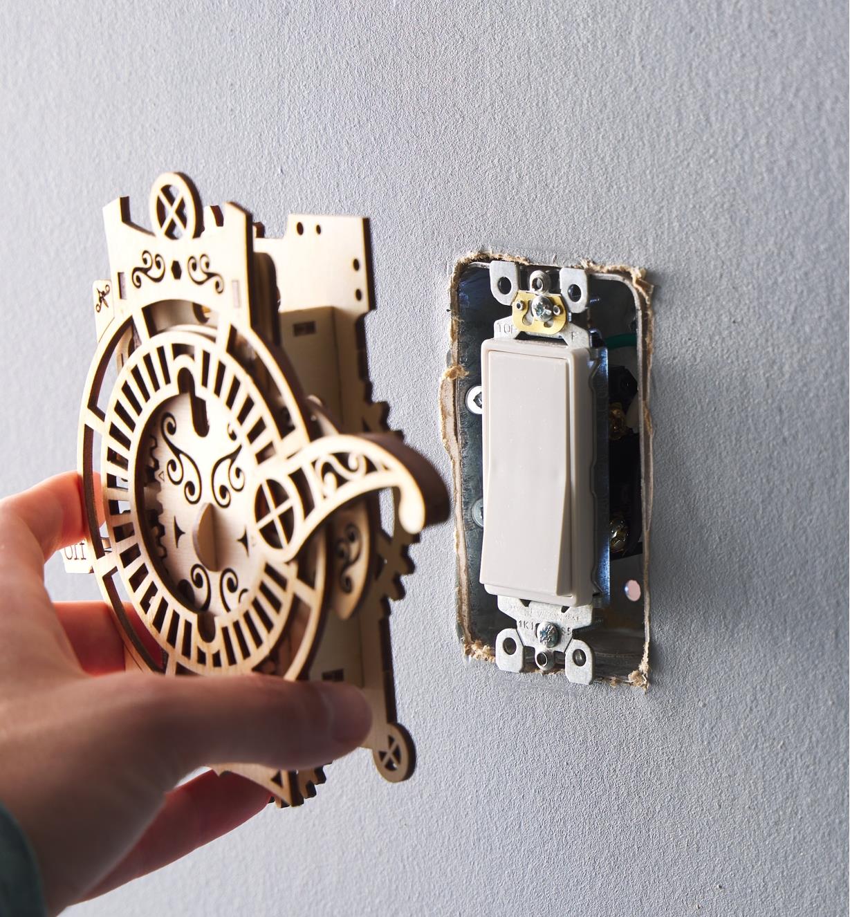 Placing the gears and lever light switch cover onto a rocker-style light switch