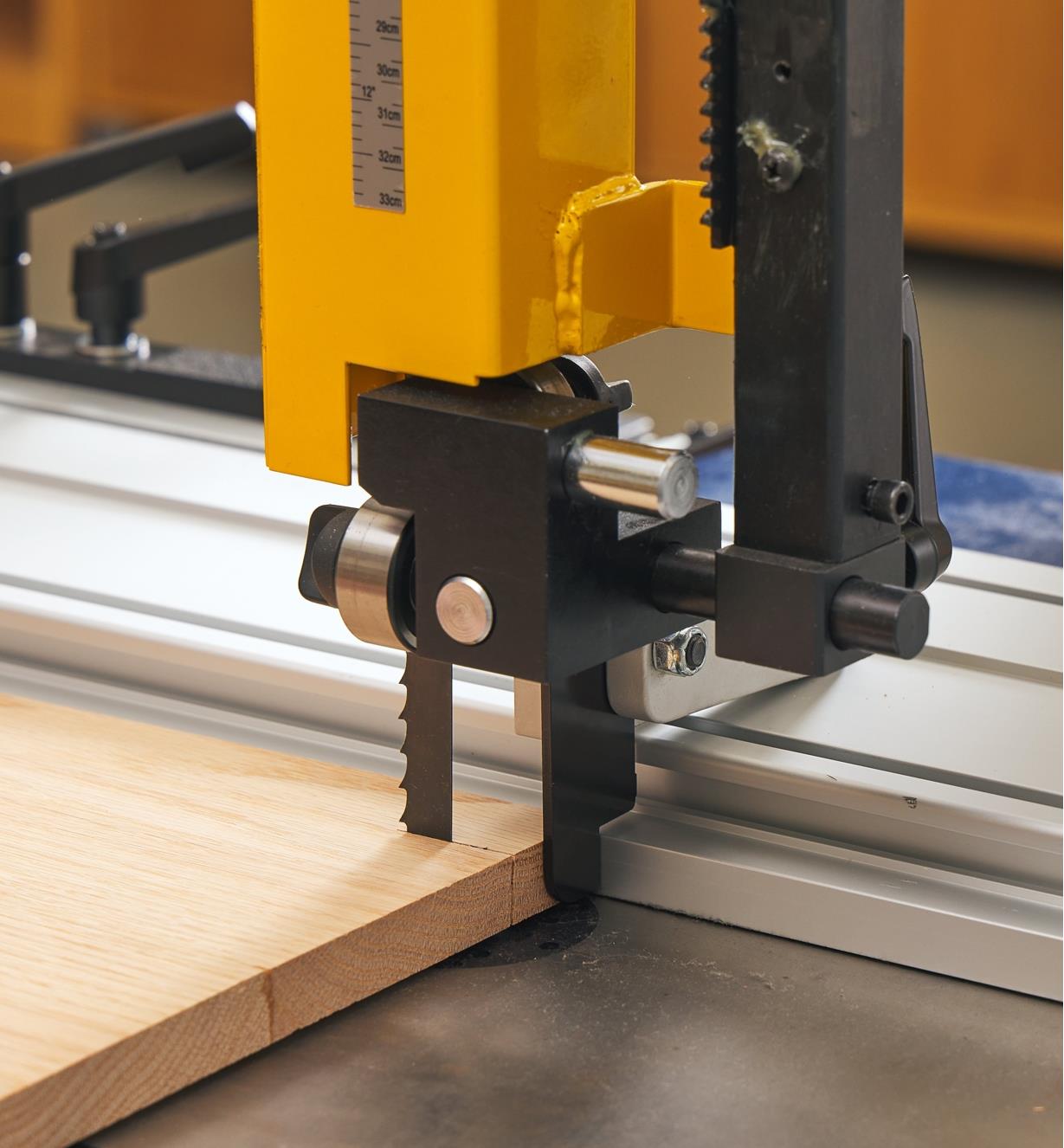 A flip stop on a DX3 Driftmaster fence limits the cut depth on a board being rip-cut on a bandsaw