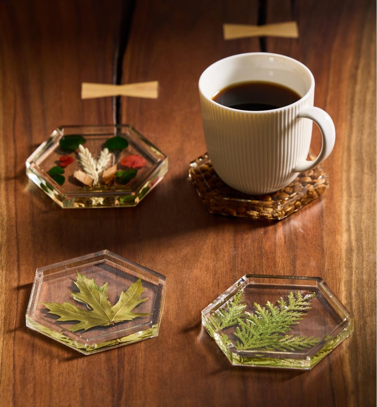 Quatre sous-verres décoratifs en résine époxy disposés sur une table dont l’un supporte une tasse de café