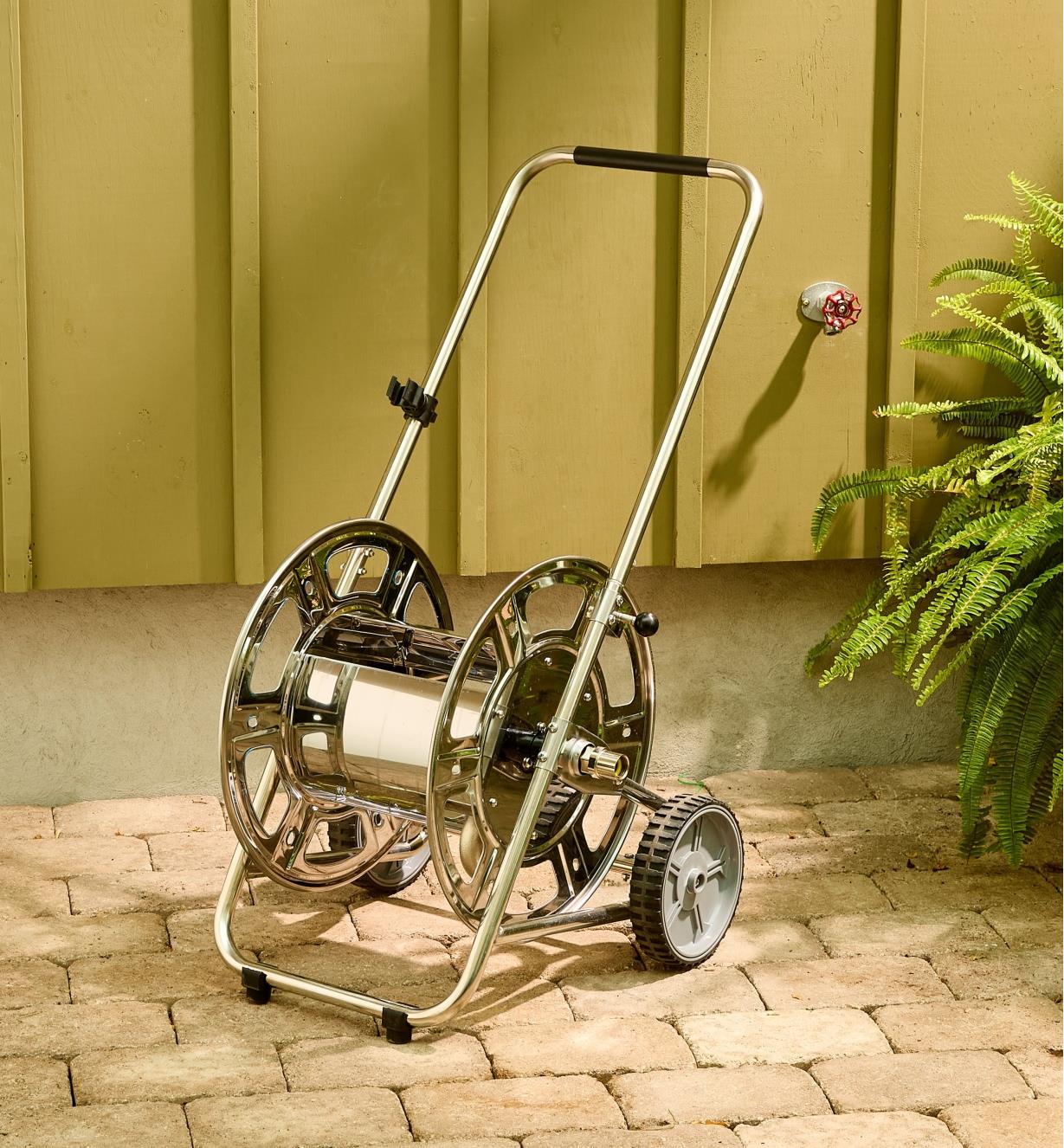 The stainless-steel hose reel cart sits empty on a patio